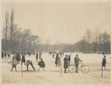 879314 Afbeelding van schaatsende en wandelende mensen op een ijsbaan, vermoedelijk in het Wilhelminapark te Utrecht.
